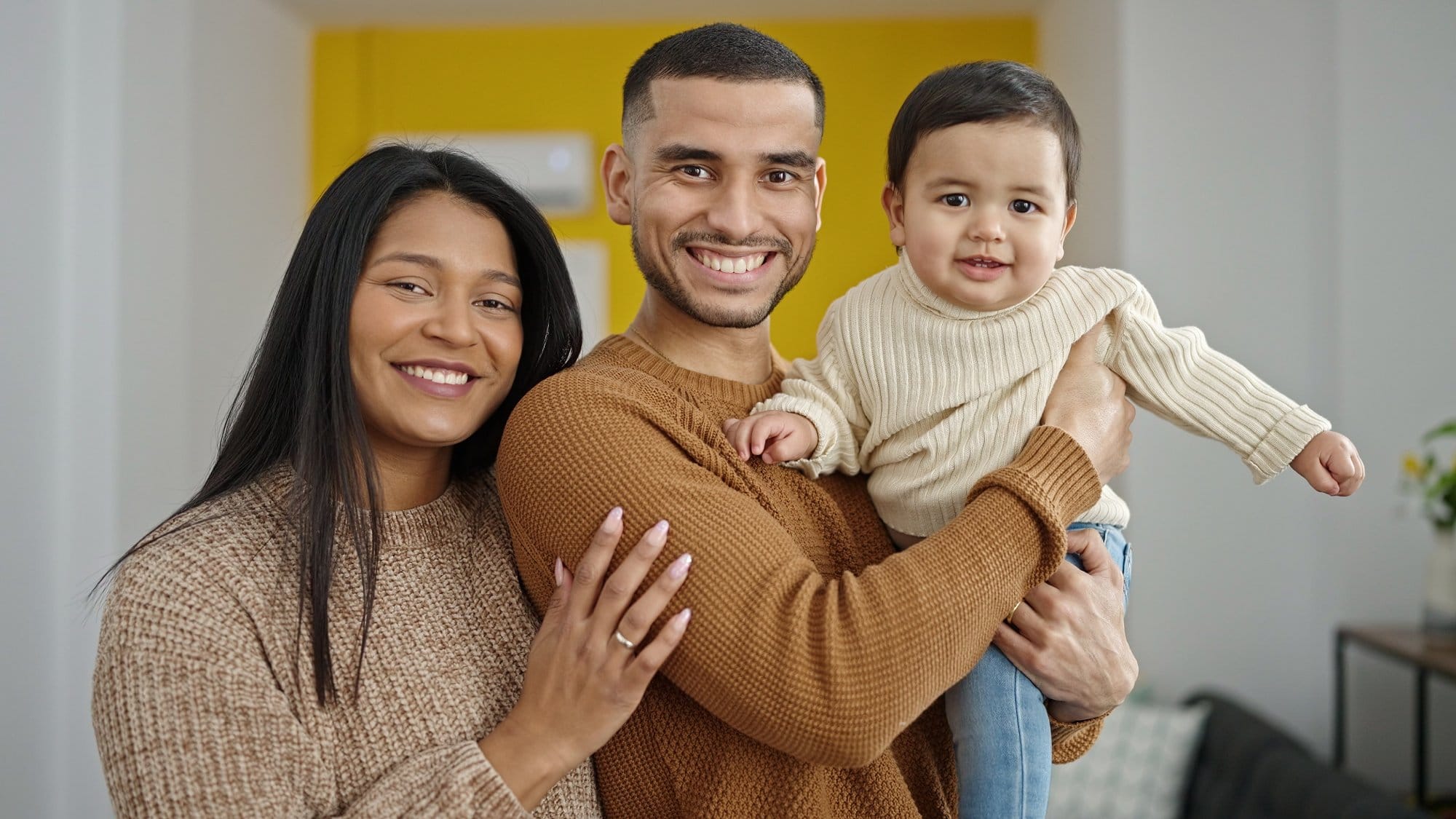 Couple and son hugging each other standing at home